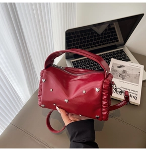 Detail of red patent leather tote with heart rivets and crystal studs on a desk