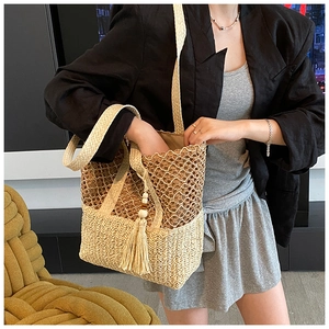 Detail of hollow-out straw tote bag with a tassel charm and wooden beads on a strap