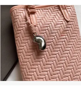 Gros plan du sac seau rose tressé avec pendentif en métal en forme de haricot