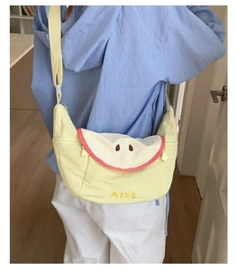 Detail of a light yellow crescent canvas bag with a creative apple shape embroidery design