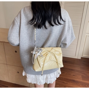 Detail of light yellow bow-knot shoulder bag with chain strap and star pendant