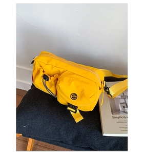 Macro detail of a yellow nylon crossbody bag featuring a functional drawstring pocket and flap