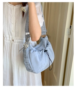 Close-up of light blue pleated dumpling bag with silver heart and butterfly charms