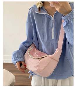 Detailed mirror shot of pink nylon crossbody bag with Erica embroidery and wide strap