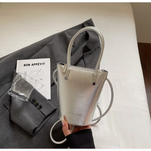 Close-up of metallic silver bucket bag with textured finish and brand embossed detail