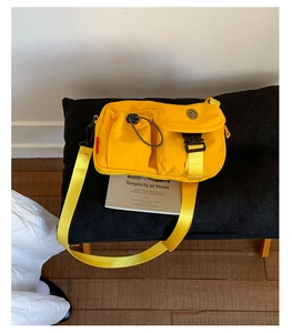 Detail of yellow canvas messenger bag featuring multiple utility pockets and buckle strap