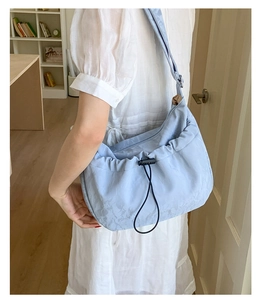 Close-up of light blue drawstring shoulder bag with a soft texture on a female model