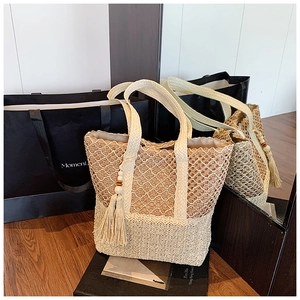 Close-up of beige straw tote bag featuring intricate openwork weave and wooden bead tassels