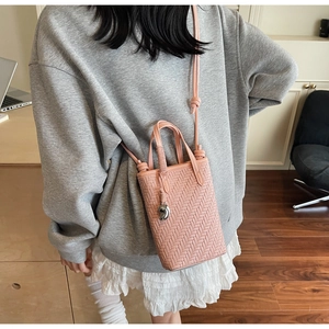 Mini sac bandoulière rose tressé avec poignée et breloque haricot argentée sur modèle