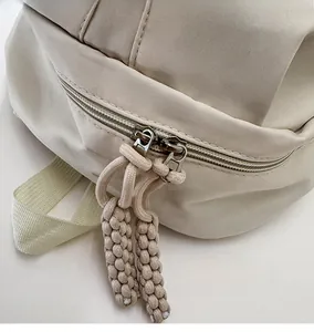 Detail of smooth double zipper with braided rope pulls on a beige canvas backpack