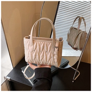 Detail of beige quilted bucket bag featuring sparkling rhinestones and gold hardware