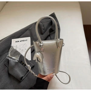 Detail of silver mirror bucket bag with cute elephant charm and thin shoulder strap