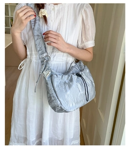 Silver pleated hobo bag with drawstring closure and silver heart charm on wide shoulder strap
