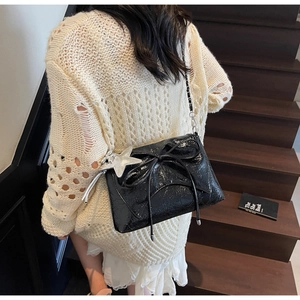 Vue détaillée du sac en cuir verni noir avec nœud papillon et étoile argentée