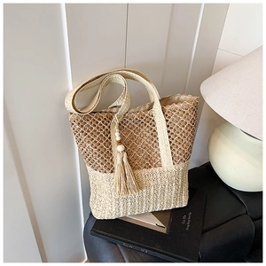 Close-up of hollow straw tote bag with woven texture, tassel beads and shoulder strap