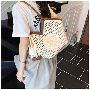 Détail du sac fourre-tout ajouré avec bordure marron et ruban de marque orné