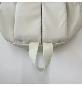 Detail of reinforced padded handle on durable beige canvas backpack for students