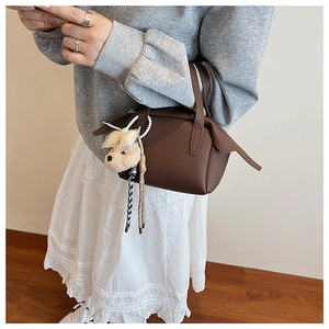Détail du sac à main marron en cuir litchi avec breloque chien et chaîne perlée