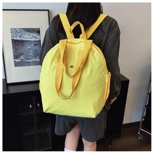 Rear view of yellow nylon convertible backpack tote with elastic side pockets and straps