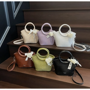 Detail view of crocodile pattern handbags in six colors with pearl heart charms