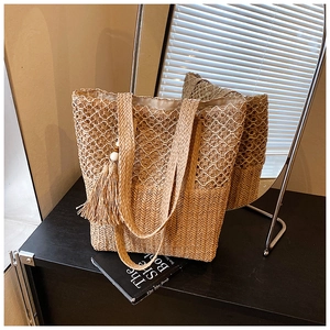 Detail of hollow-out straw tote bag with tiered weaving patterns and tassel charm