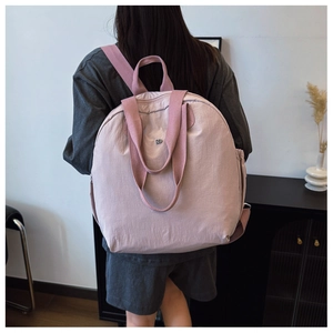 Pale pink puffer backpack shown on model highlighting the ultra-lightweight nylon material
