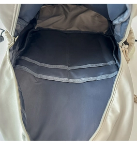 Detailed view of the spacious inner storage and compartments of this beige backpack