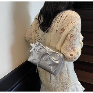 Détail du sac bandoulière argenté brillant avec nœud élégant et chaîne en métal