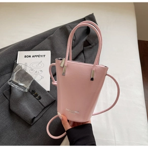 Detail of light pink leather bucket bag showing silver fashion logo and zip closure