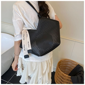 Détail du cabas en cuir noir ajouré avec bandoulière tissée à motifs élégants