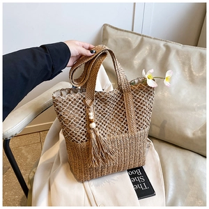 Close-up of handmade straw woven bag texture with wooden bead tassel and hollow mesh detail