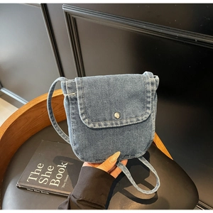 Detail of blue denim crossbody bag featuring white contrast stitching and a metal snap button