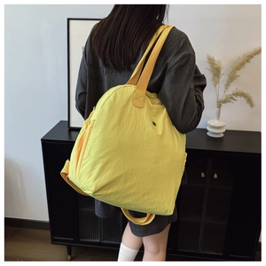 Detail of waterproof nylon backpack with side pockets and wide shoulder straps in bright yellow