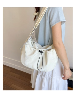 Detail of off-white pleated dumpling bag with drawstring and silver butterfly pendant
