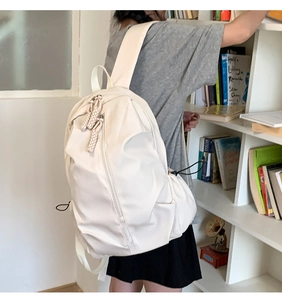 Detail view of large beige nylon backpack with woven zipper pulls and side drawstring design