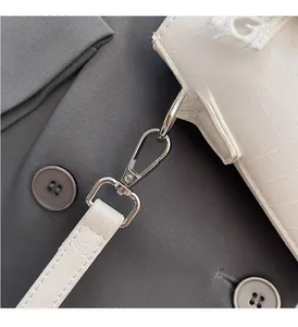 Macro detail of silver hardware and crocodile pattern leather on white bucket bag