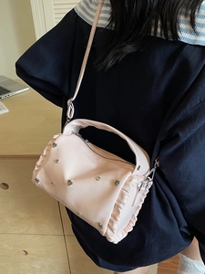 Pink PU leather tote bag with silver heart rivets and ruffle edge details shown in use
