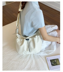 Detailed shot of a beige drawstring crossbody bag with black adjusters and wide strap