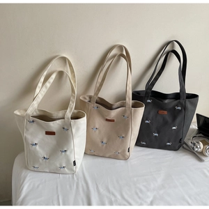 Detail of embroidered dog patterns on large canvas tote bags in white and grey colors