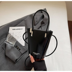 Detail of black patent leather bucket bag with high gloss finish and delicate silver hardware