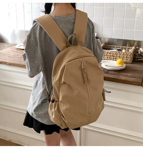 Detail of khaki nylon backpack featuring wide padded straps and a vertical zipper design
