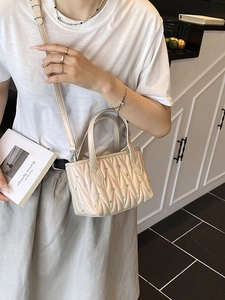 Elegant beige quilted bucket bag with chain strap and rhinestone accents for women