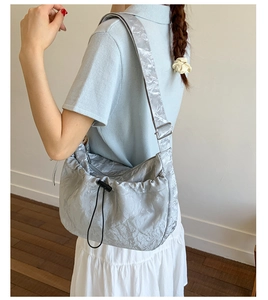 Detail showing crinkled liquid silver fabric texture and black drawstring of the hobo bag