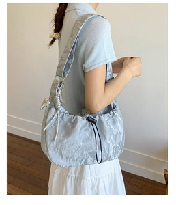 Detail of silver pleated dumpling bag showing drawstring closure and heart charm