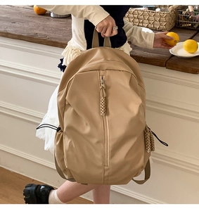 Detail of khaki backpack featuring braided rope zipper pulls and side drawstring pocket