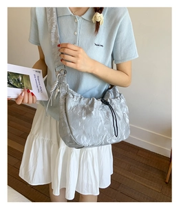 Detail of silver metallic pleated dumpling bag with drawstring and wide shoulder strap