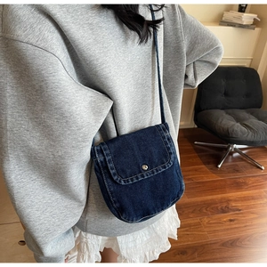 Detail view of dark blue denim crossbody messenger bag shown on model for daily style