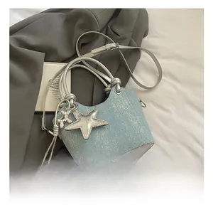 Detail of light blue denim bucket bag with silver star and balloon dog charm on grey suit