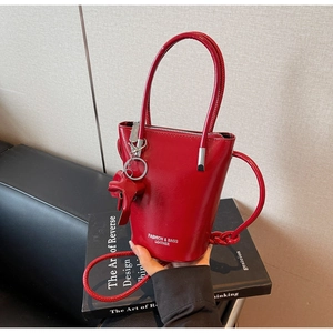 Detail of red shiny leather bucket bag with silver zipper and star charm on books