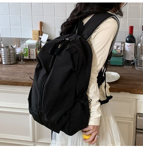 Side view of black high-capacity canvas backpack with wide shoulder straps on model